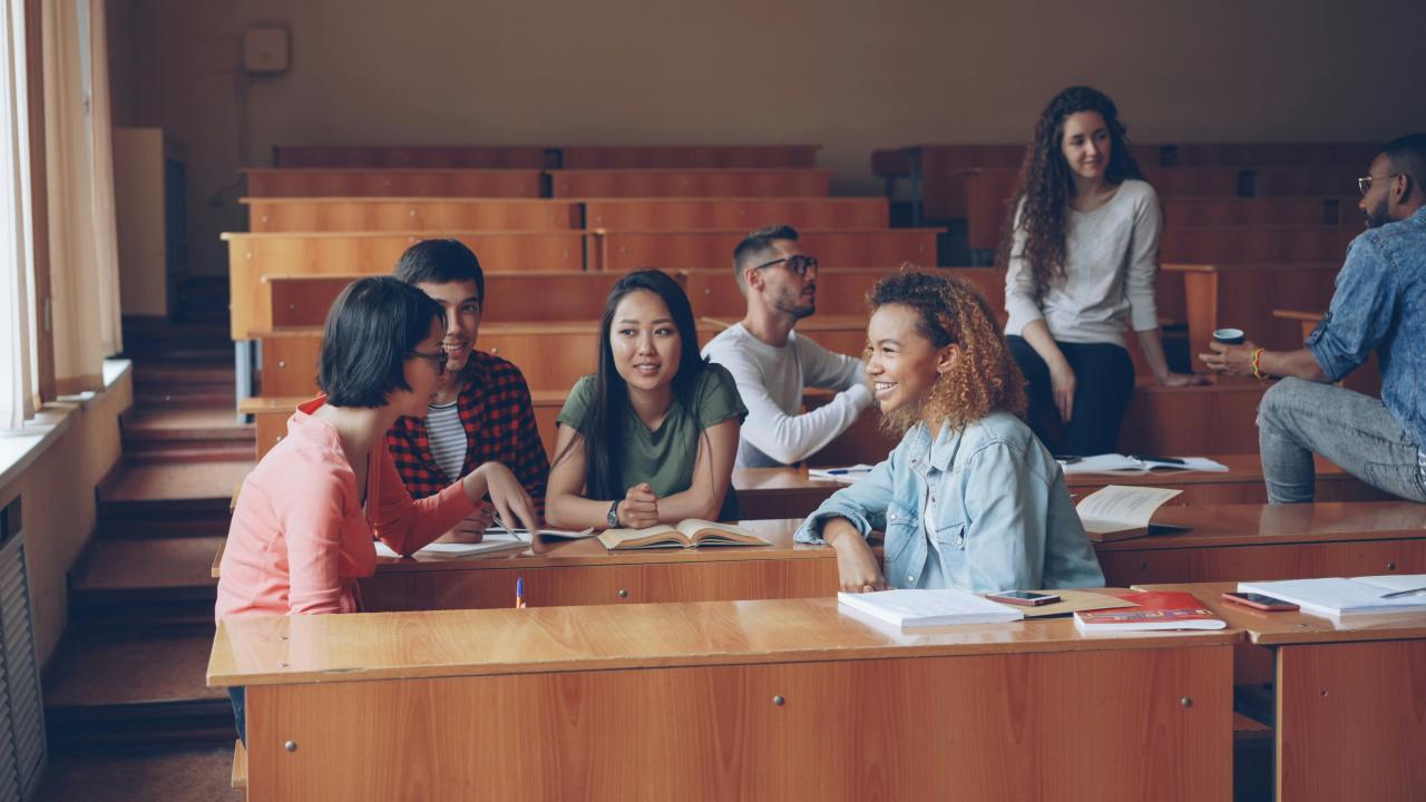 Students talking and studying in a lecture hall.
